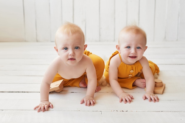 infant twins in orange suits posing