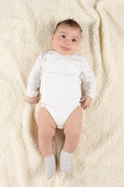 An infant in a white bodysuit lies on a soft blanket Mockup for advertising design celebration postcards