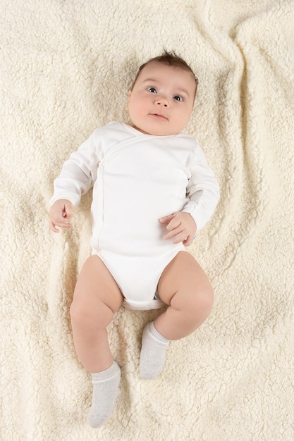 An infant in a white bodysuit lies on a soft blanket Mockup for advertising design celebration postcards