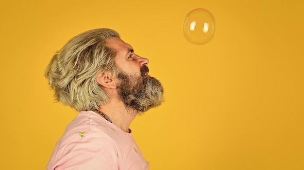 Infantility concept Happy playful bearded hipster and soap bubbles Happiness and joy Good vibes Blow inflate bubbles Forever young guy Positive Carefree man soap bubbles Summer vacation