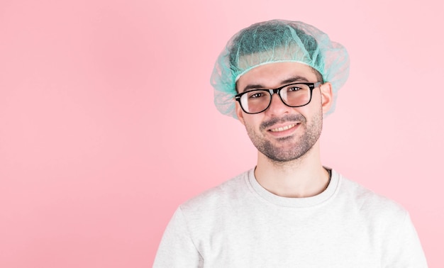 Infectious disease physician. Portrait of confident healthcare professional in protective mask and fluffy cap  on pink wall