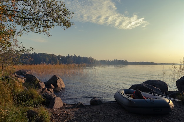 Inflatable boat with a fishing rod and a life jacket on the background of a foggy lake. summer evening.