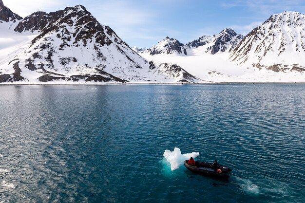 Photo inflatable boat with one person in arctic waters, svalbard. pushing ice.