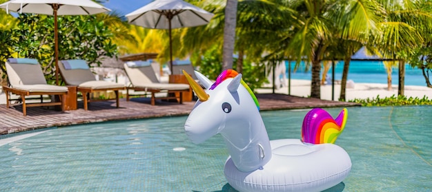 Inflatable colorful white unicorn at resort swimming pool. Vacation time in tropical pool fun