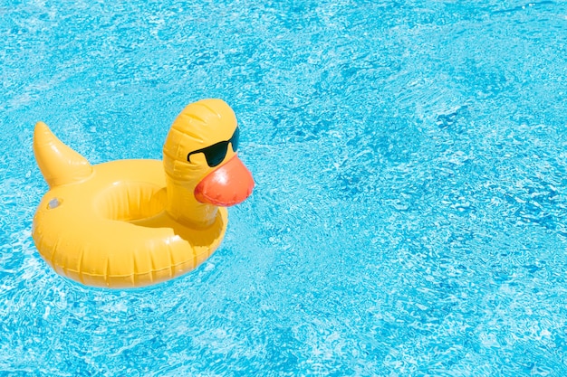 An inflatable duck on a background of swimming pool water summer and travel concept copy space