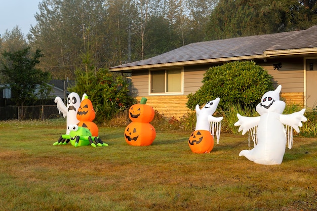 Inflatable figures of ghosts, spider and pumpkins near house. Outdoor Halloween decorations