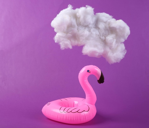 Inflatable flamingo with cloud on purple background Creative idea Summer fun Minimal concept