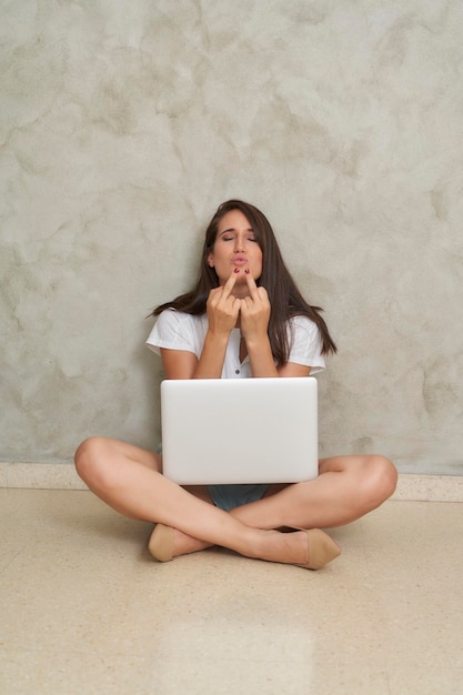 Influencer teleworking sitting on the floor raising her finger flip off fuck off kiss lips