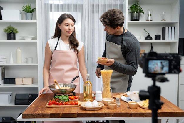 Photo influencers on cooking show presenting ingredient of spaghetti dish postulate