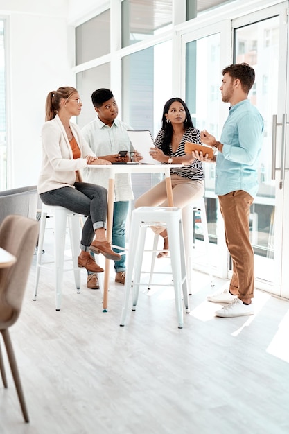 Informal discussions Full length shot of a group of young business colleagues gathered around a table in their office