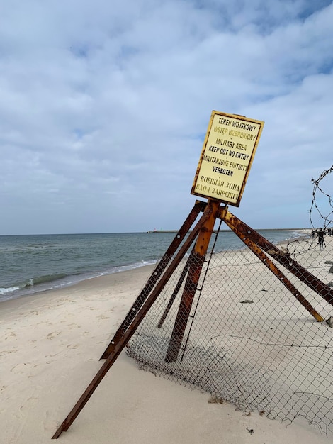 Photo information sign on beach against sky