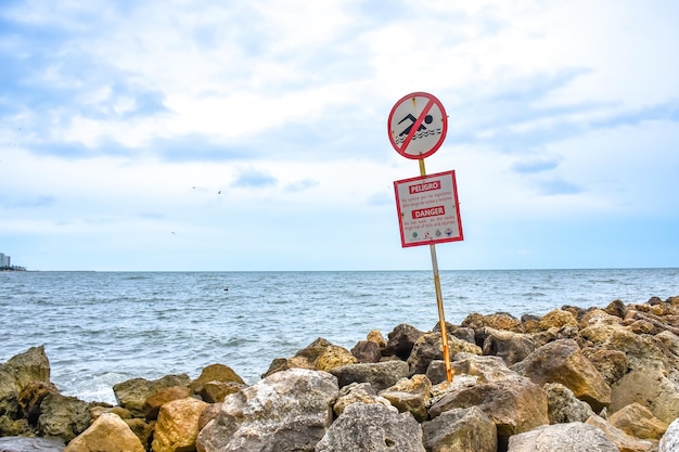 Information sign on rock by sea against sky