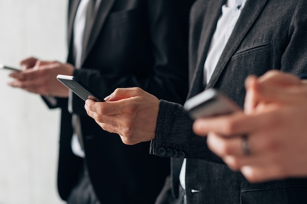 Information technology in modern corporate world. Cropped shot of business men standing in row with smartphones.