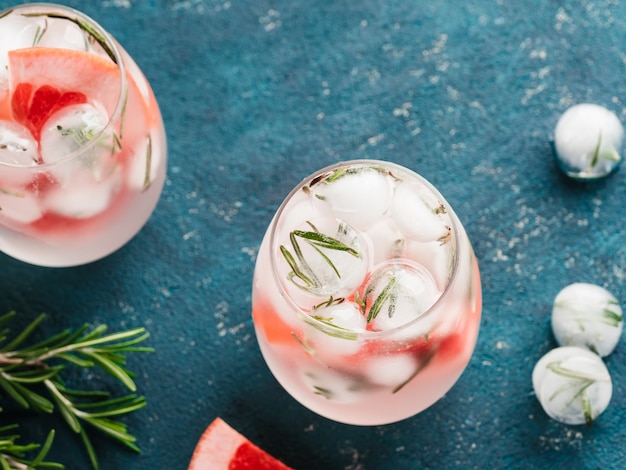 Infused detox water or alcoholic or non-alcoholic cocktail with grapefruit and rosemary ice in glass