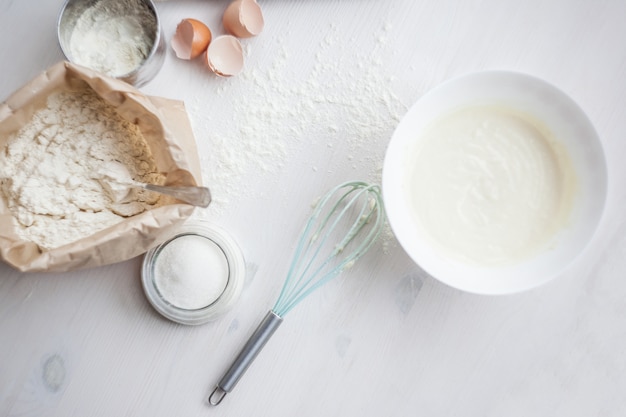 Ingredients for baking cake laid out on a white wooden table. selective focus