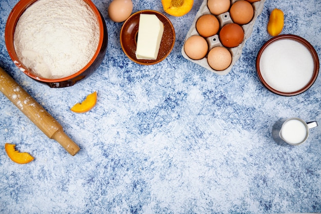 Ingredients for baking - eggs,flour,sugar,butter,milk on a light blue concrete,stone or slate background. Top view with space for text.