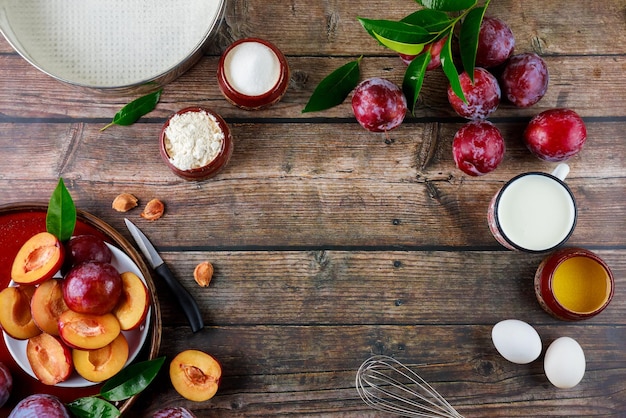 The ingredients of the baking process are eggs whisk plums and a baking pan