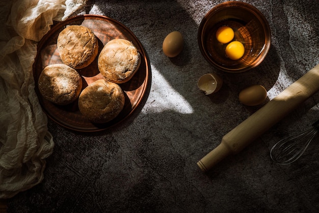 Ingredients for baking rye buns rolling pin eggs on a gray table illuminated by the sun 1