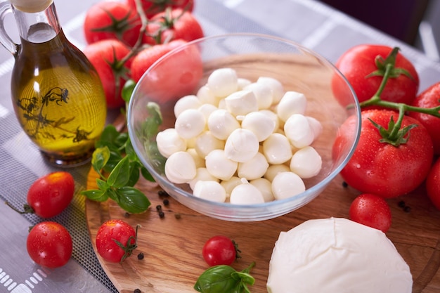 Photo ingredients for caprese salad mini mozzarella cheese in glass bowl tomato and basil