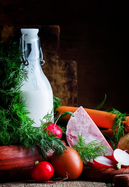 Ingredients for cold soup with vegetables herbs and meat products old wooden table selective focus.