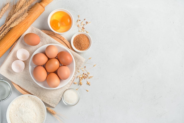 Ingredients for cooking on a gray background. Eggs, flour, sugar, pastries. Top view, copy space.