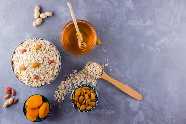 Ingredients for a healthy breakfast, nuts, oatmeal, honey, dried apricots, almonds, peanuts. Concept of natural organic food