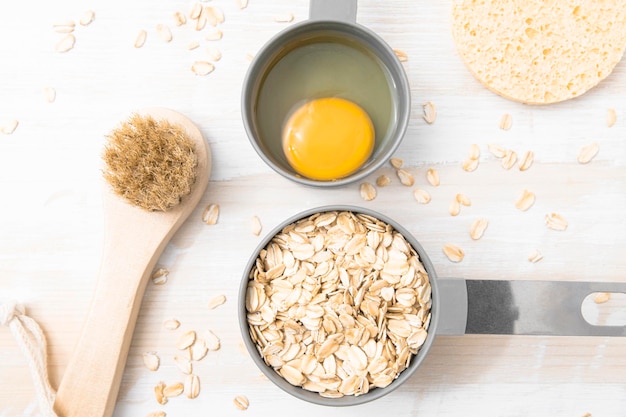 Ingredients for a homemade cosmetic mask on a wooden table oatmeal and egg for strengthening hair