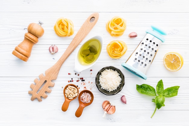 The ingredients for homemade pesto pasta on white wooden background.