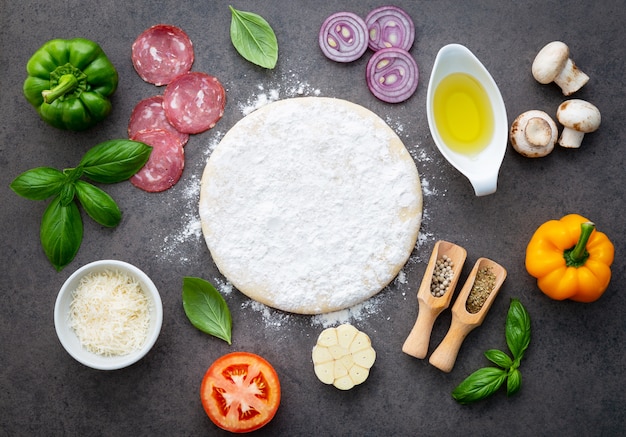 The ingredients for homemade pizza on dark stone background.