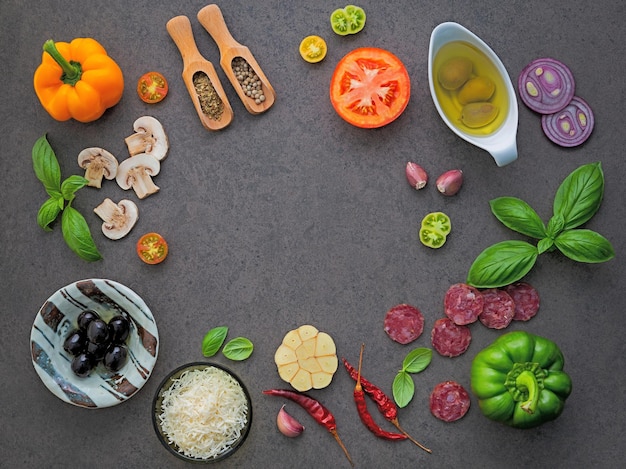 Photo the ingredients for homemade pizza on dark stone background