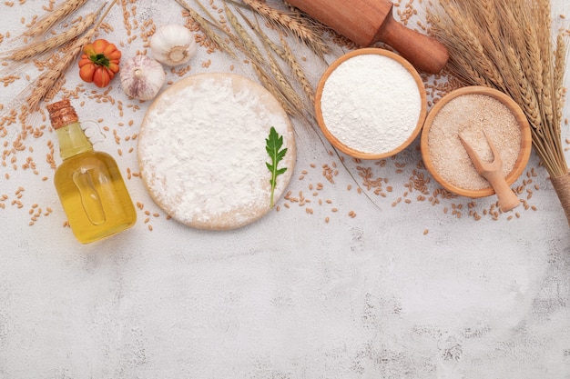 the ingredients for homemade pizza dough set up on white concrete background.