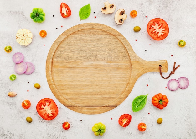 The ingredients for homemade pizza set up on white concrete background.