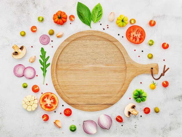 The ingredients for homemade pizza set up on white concrete background.