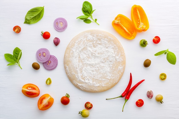 The ingredients for homemade pizza on white wooden background.