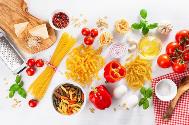 Ingredients for italian cousine flat lay, pasta spaghetti penne fusilli tomato oil vegetables