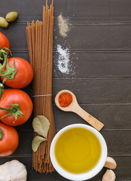 Ingredients of Italian cuisine. Culinary background for recipes. Diet or vegan food. Top view of Italian spaghetti, tomatoes, garlic, olive oil and bay leaves.