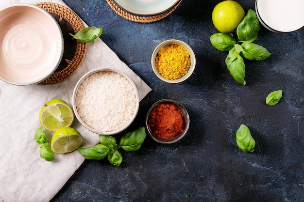 Ingredients for making a bowl of yellow curry served with basil, rice and limes