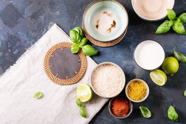 Ingredients for making a bowl of yellow curry served with basil, rice and limes