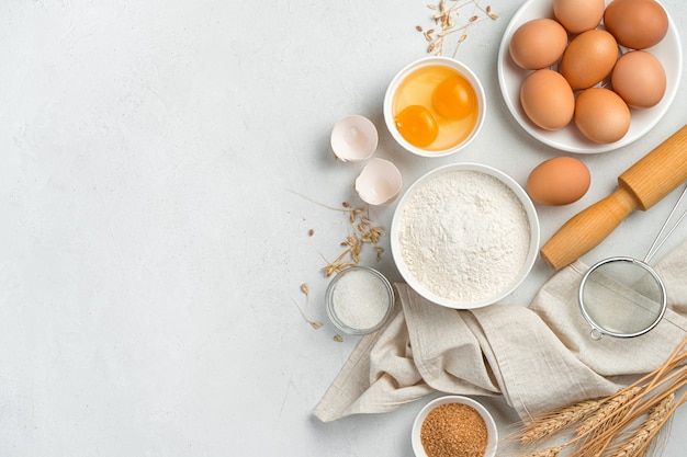 Ingredients for making dough dishes: cakes, cookies, pizza, pasta on a gray background. Flour, eggs, and sugar. Top view, copy space.