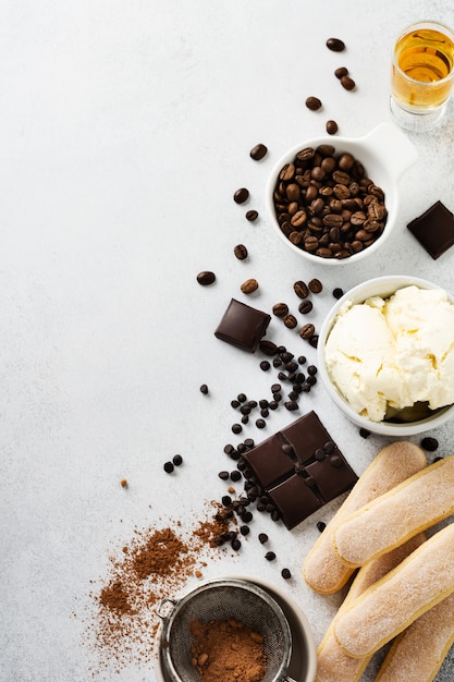 Ingredients for making Italian dessert tiramisu, savoiardi, mascarpone, cocoa powder and chocolate on a light concrete