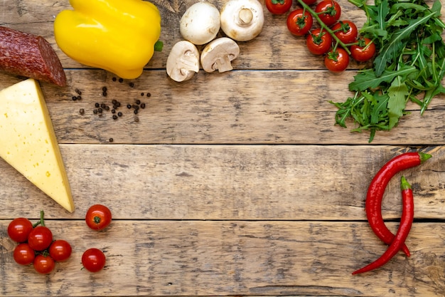 ingredients for making pizza on a wooden table with space for text, top view