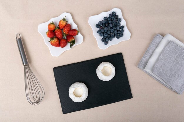 Ingredients for meringue cakes with berries and whisk Cake Anna Pavlova Top view