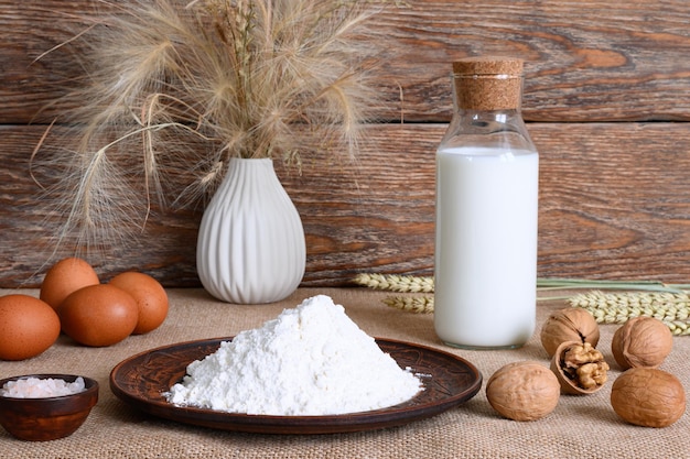 Ingredients for pancake batter vase apple and walnuts on wooden background