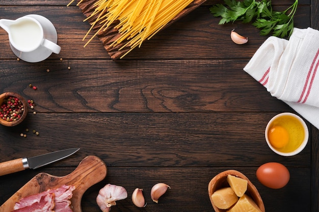 Ingredients for Pasta Carbonara Traidtional Italian Pasta Carbonara Ingredients bacon spaghetti parmesan and egg yolk garlic Dark wooden old table background Top view Copy space