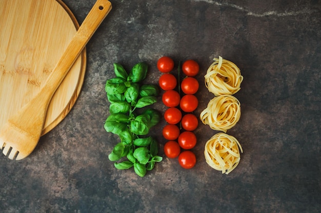 Ingredients for pasta dark background basil cherry tomatoes spaghetti tagliatelle Italian flag