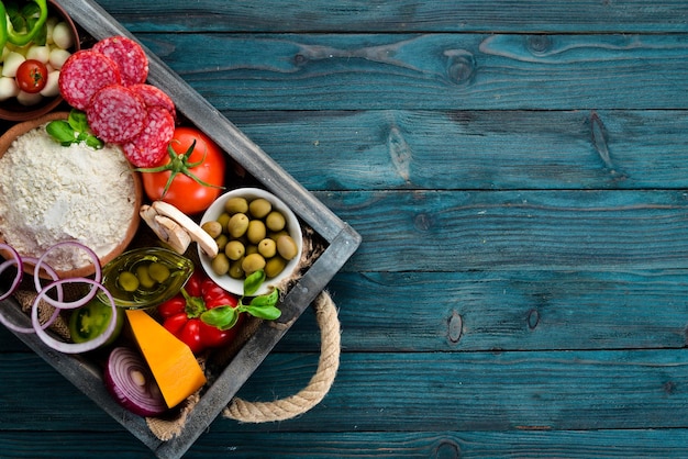 Ingredients for pizza in a wooden box Top view On a wooden background Free copy space