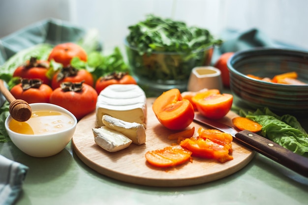 Ingredients and the process of making a vitamin winter salad with persimmons tangerines and cheese