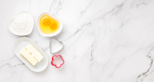 Ingredients and shapes for baking cookies on marble table. Concept cooking with love, cooking for your loved ones, baking for valentines day. Top view. Copy space