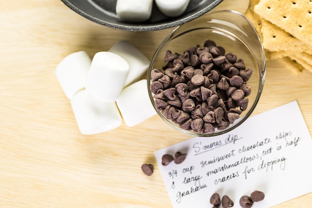 Ingredients smores dip prepared with large marshmallows in cast iron pan.