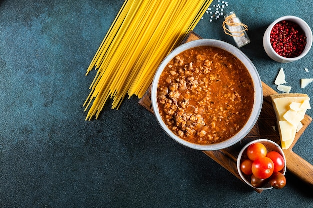 Ingredients for spaghetti bolognese on dark background. Raw pasta bolognese. Pasta flatlay. Italian bolognese. Food ingredients. Pasta top view